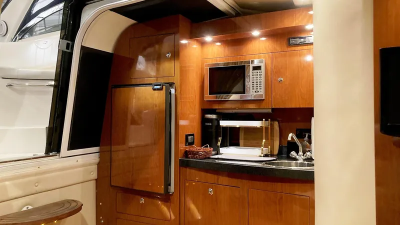 Slide: The Image of 2008 Regal 3760 yacht interior kitchen with microwave, fridge, and wooden cabinetry. - 38