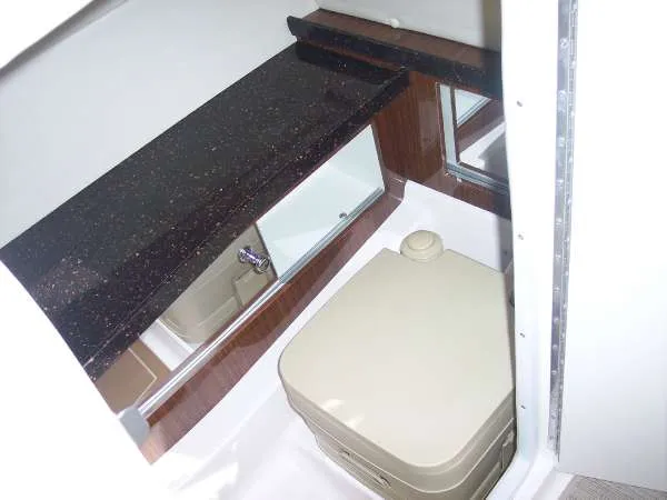 Slide: The Image of 2014 Regal 24 FasDeck boat bathroom with compact toilet and dark countertop. - 18