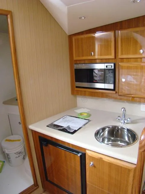 Slide: The Image of 2024 Jersey Cape Devil 36 Custom yacht kitchen with microwave, sink, and wooden cabinets. - 11