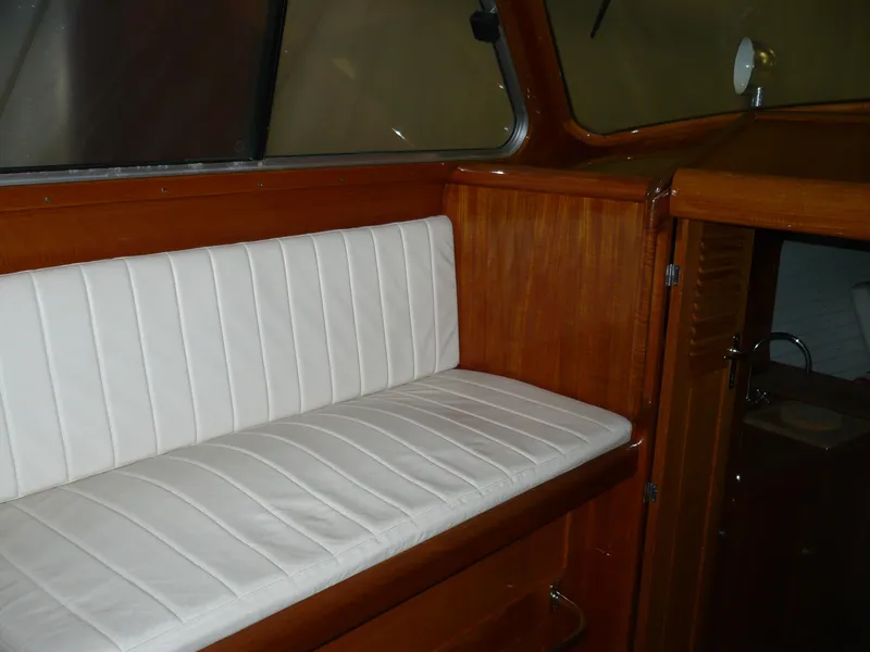 Slide: The Image of Interior of 1999 Classic Coaster Picnic Boat with white cushioned seating and wooden paneling. - 10