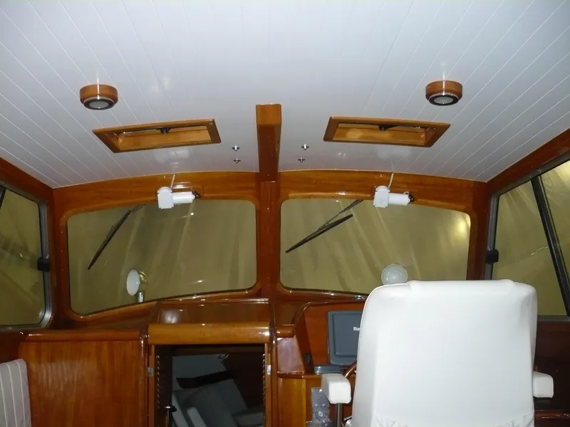 Slide: The Image of Interior of a 1999 Classic Coaster Picnic Boat with wooden accents and white seating. - 12