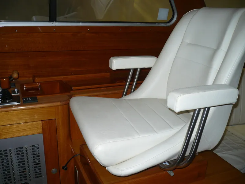 Slide: The Image of White captain's chair in 1999 Classic Coaster Picnic Boat, featuring wooden interior and control panel. - 16