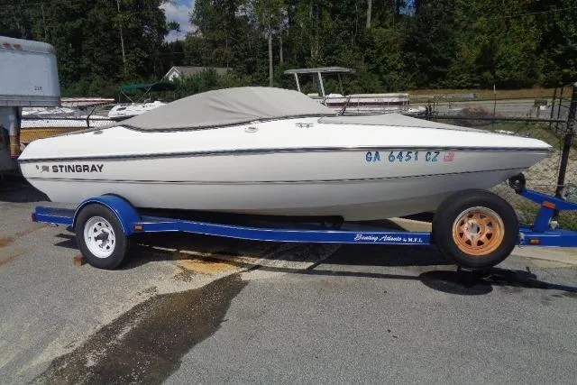 The Image of 2005 Stingray 180RX boat on a blue trailer, parked outdoors. - 0
