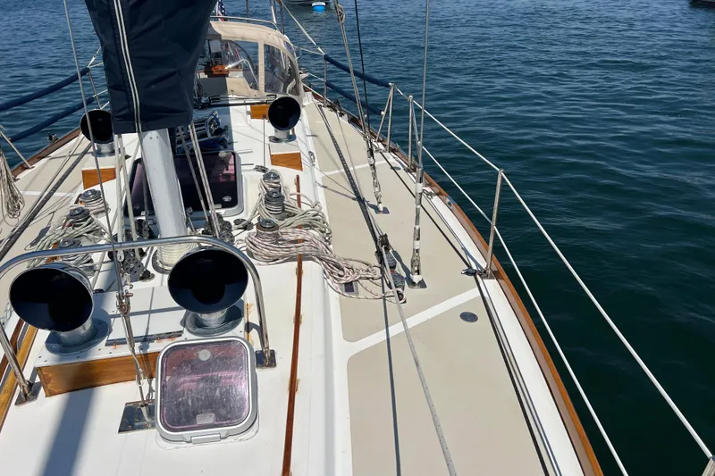 Slide: The Image of 1980 Hinckley 43 sailboat deck with ropes and winches on calm water. - 48