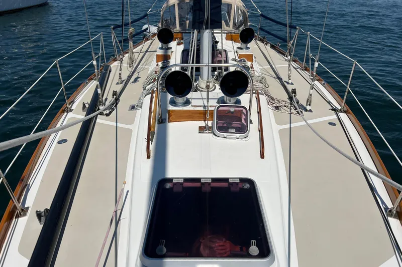 Slide: The Image of 1980 Hinckley 43 sailboat deck with ropes and hatches on calm water. - 49