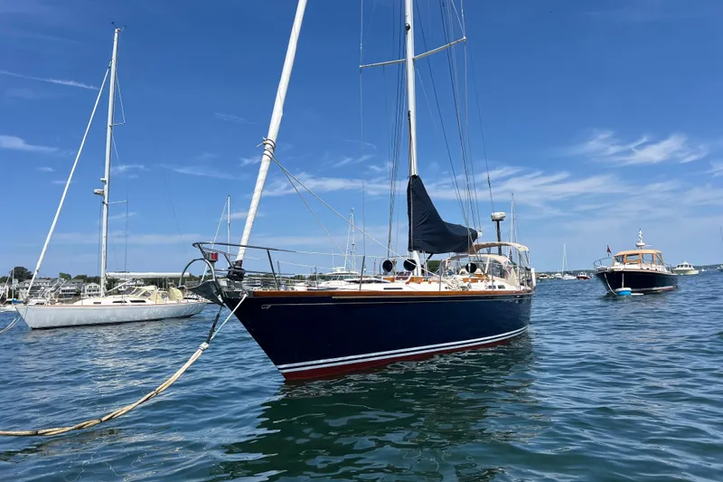 Slide: The Image of 1980 Hinckley 43 sailboat anchored in a sunny harbor with clear blue skies. - 59