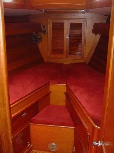 Slide: The Image of 1980 Hinckley 43 yacht cabin with red cushions and wooden interior. - 6