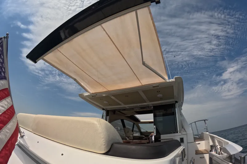 Slide: The Image of Azimut 55S yacht, 2016 model, with sunshade and American flag, under a clear sky. - 32