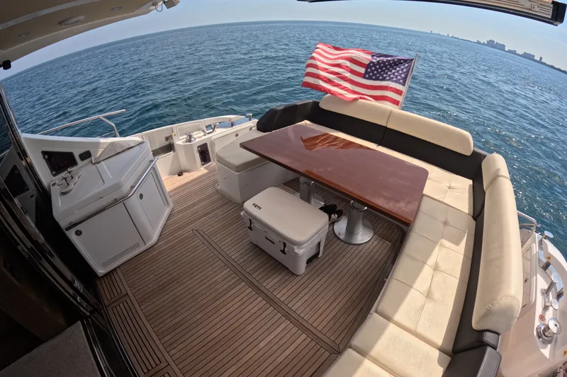 Slide: The Image of Luxurious 2016 Azimut 55S yacht deck with seating, table, and American flag on open sea. - 29