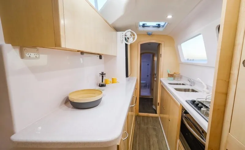 Slide: The Image of Modern kitchen in 2024 Seawind 1260 Owners Version catamaran with light wood cabinetry. - 32