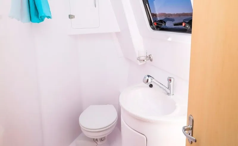 Slide: The Image of 2024 Seawind 1260 Owners Version bathroom with toilet, sink, and window. - 35