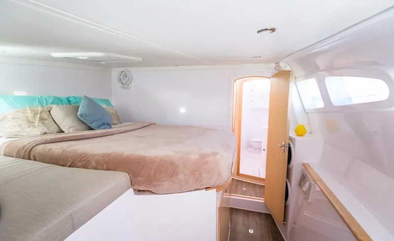 Slide: The Image of Seawind 1260 Owners Version 2024 bedroom with cozy bed and ensuite bathroom. - 36