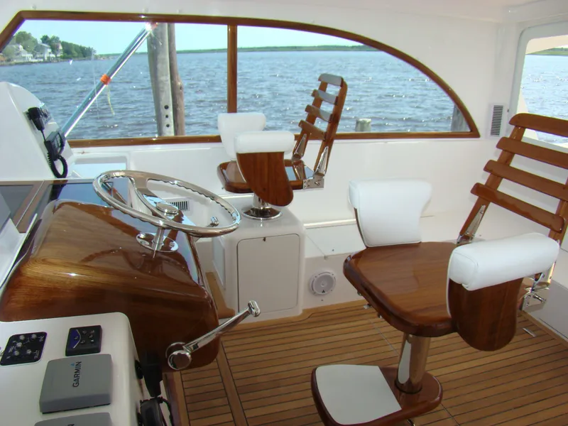 Slide: The Image of Interior of 2024 Jersey Cape 47 Custom Hardtop boat with wooden helm and seating. - 17
