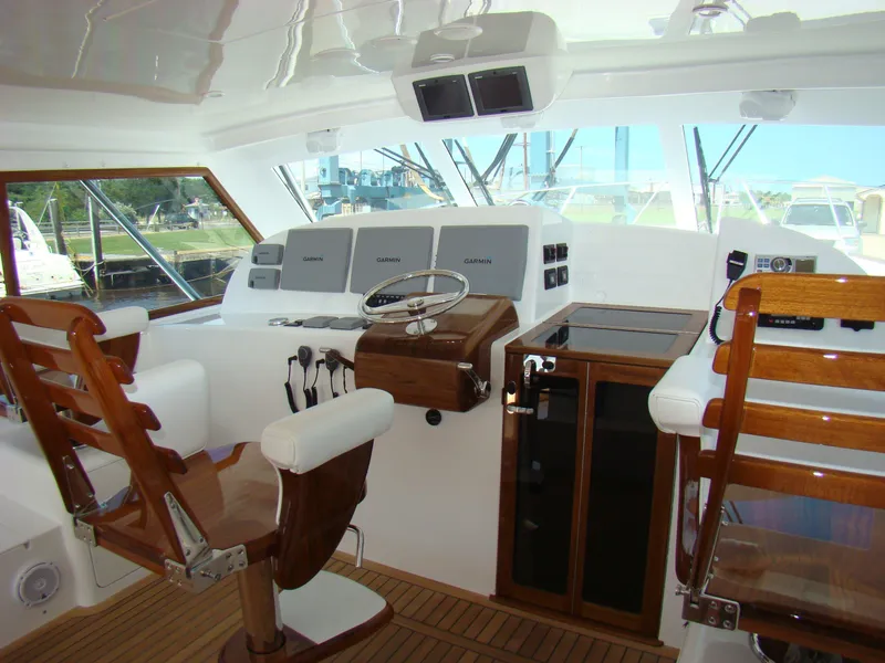Slide: The Image of 2024 Jersey Cape 47 Custom Hardtop helm station with wooden chairs and modern navigation equipment. - 20