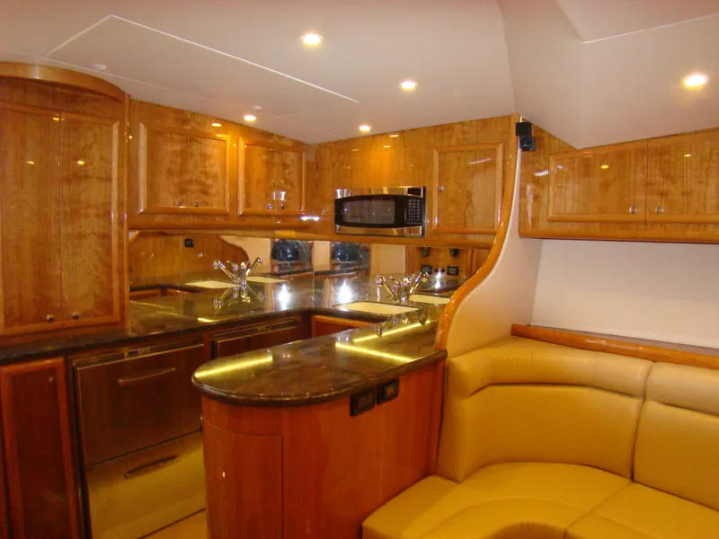 Slide: The Image of 2024 Jersey Cape 47 Custom Hardtop yacht interior with modern kitchen and seating area. - 6
