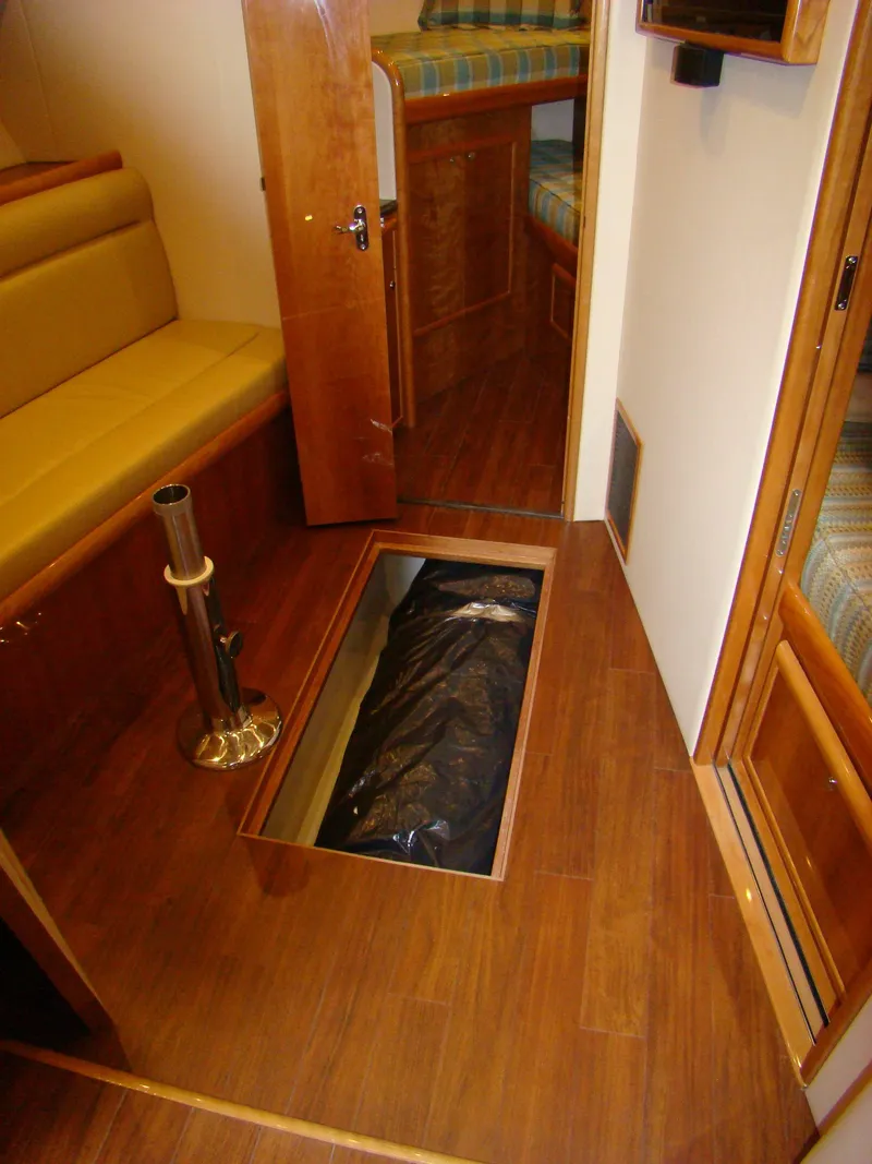 Slide: The Image of 2024 Jersey Cape 47 Custom Hardtop interior with wooden flooring and storage compartment. - 9