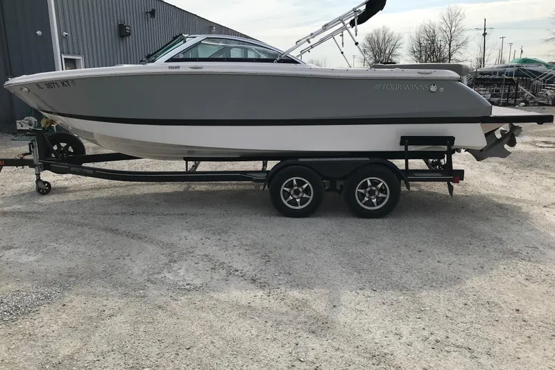 Slide: The Image of 2015 Four Winns H230 boat on trailer, parked outdoors near a building. - 16