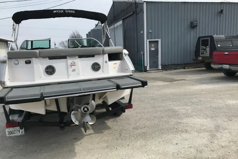 Slide: The Image of 2015 Four Winns H230 boat parked near a metal building and red truck. - 20