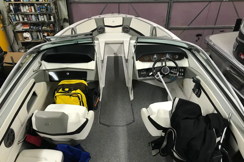 Slide: The Image of 2015 Four Winns H230 boat interior with steering wheel, seats, and storage compartments. - 30
