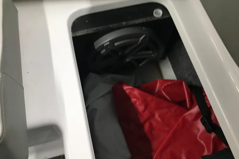 Slide: The Image of Storage compartment in 2015 Four Winns H230 boat with red bag and speaker. - 38