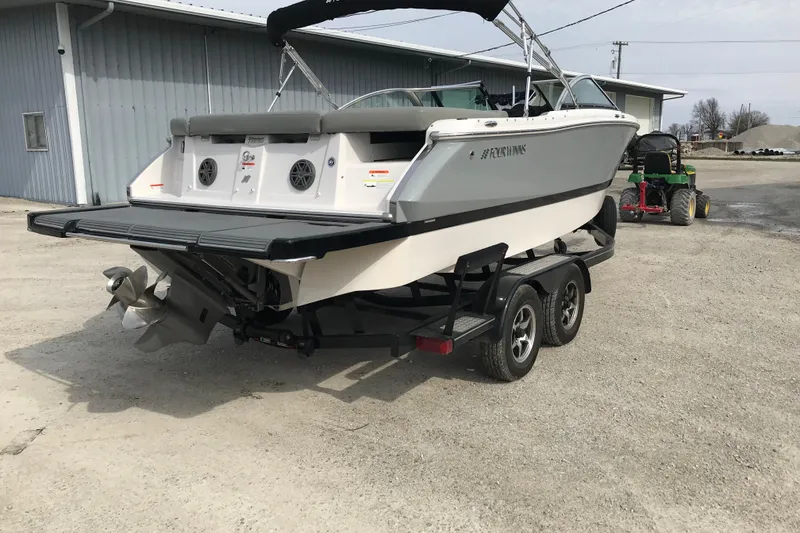 Slide: The Image of 2015 Four Winns H230 boat on trailer, parked outdoors near a building. - 6