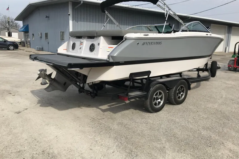 Slide: The Image of 2015 Four Winns H230 boat on trailer, parked outside a building. - 7