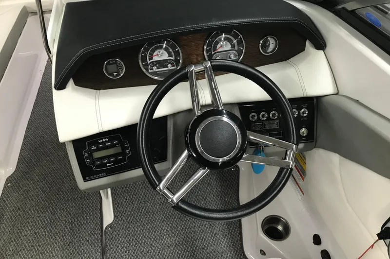 Slide: The Image of Steering wheel and dashboard of 2015 Four Winns H230 boat, featuring gauges and controls. - 70