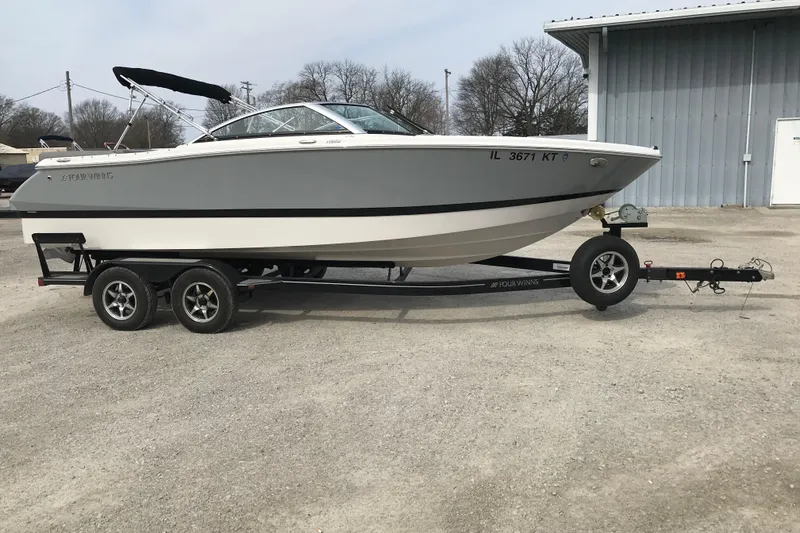 Slide: The Image of 2015 Four Winns H230 boat on trailer, parked outdoors near a metal building. - 9