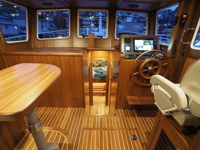 Slide: The Image of Helmsman Trawlers 43E PILOTHOUSE 2026 interior with wooden finish and navigation equipment. - 12