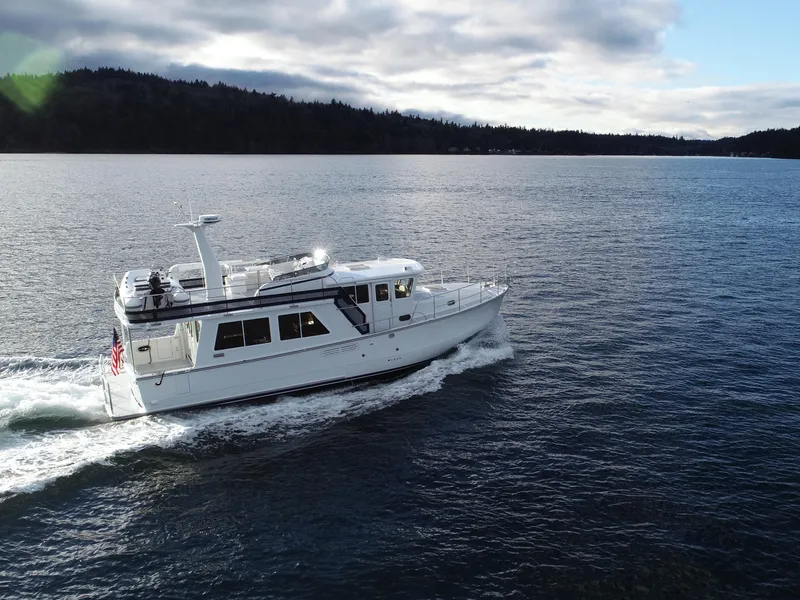 Slide: The Image of 2026 Helmsman Trawlers 43E Pilothouse cruising on a serene lake under cloudy skies. - 3