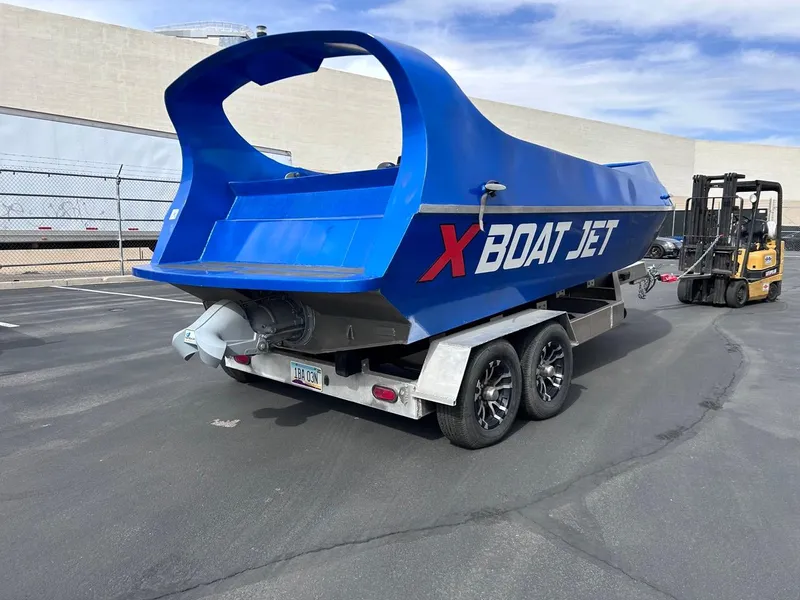 Slide: The Image of Blue Smoky Mountain 12 Passenger X Boat Jet on trailer, parked in industrial area. - 2