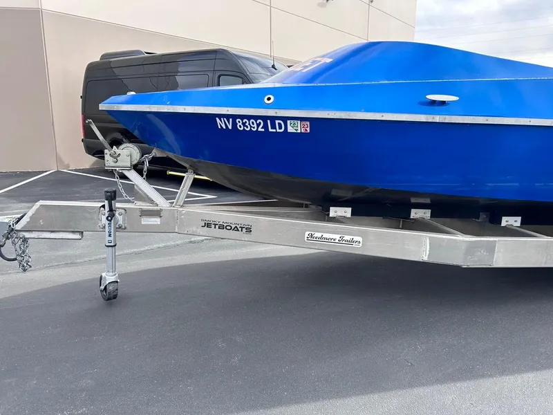 Slide: The Image of 2021 Smoky Mountain 12 Passenger boat on trailer, blue hull, parked outdoors. - 6