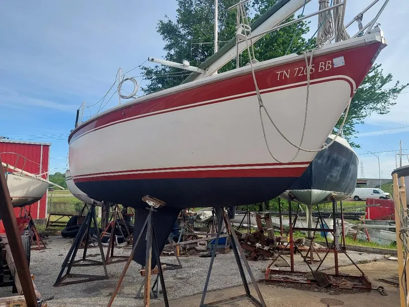 The Image of 1981 CAL 25II Mk II sailboat on stands, red and white hull, outdoors. - 0
