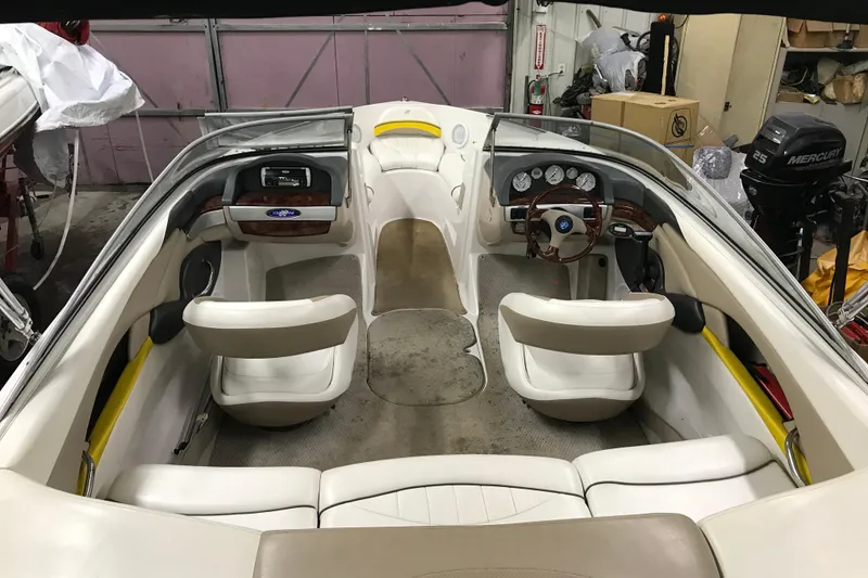 Slide: The Image of 2005 Four Winns 190 Horizon boat interior with white seating and wood-accented dashboard. - 14