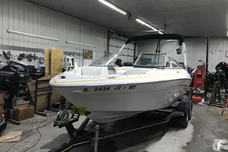 Slide: The Image of 2005 Four Winns 190 Horizon boat in a garage, on a trailer, with visible equipment. - 8