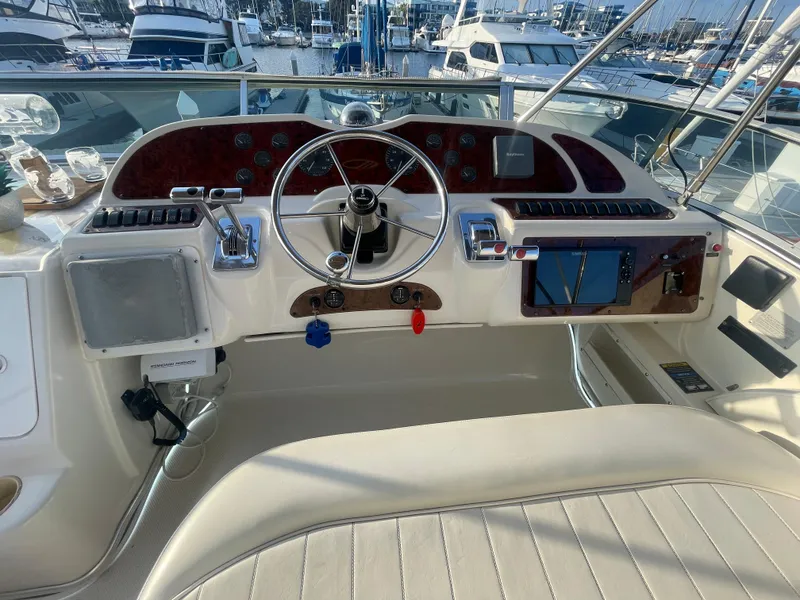 Slide: The Image of 1998 Maxum 4100 SCA yacht helm with steering wheel and navigation controls at marina. - 12
