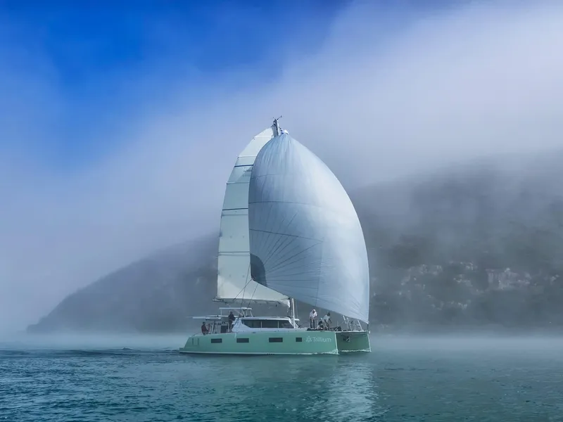 Slide: The Image of Sailboat Vision 444 ES 2026 navigating through misty waters with large white sail. - 2