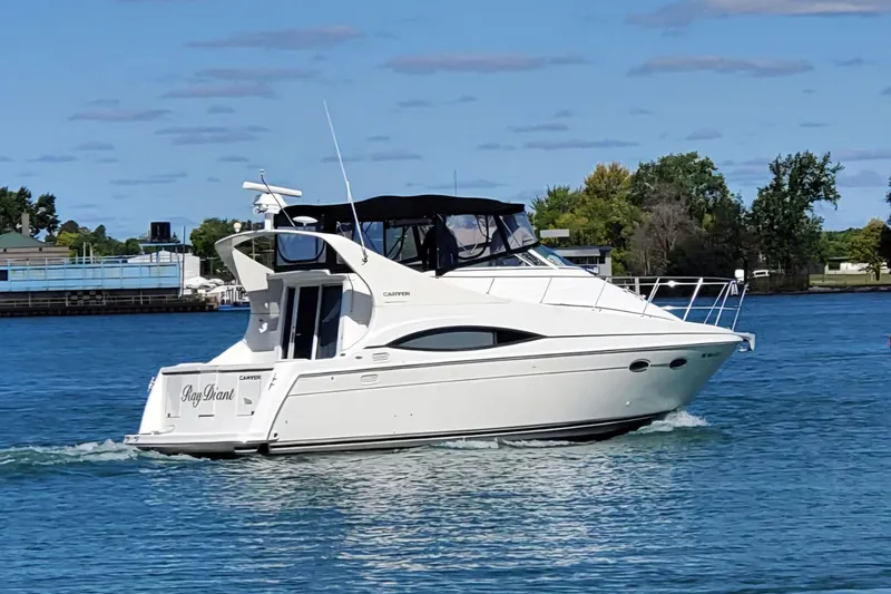 Slide: The Image of 1997 Carver 350 Mariner yacht cruising on a sunny day, surrounded by blue water and trees. - 1