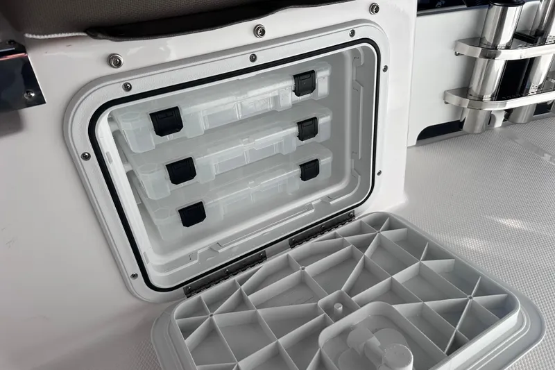 Slide: The Image of Open storage compartment on 2026 Edgewater 170CC boat with organized tackle boxes. - 10