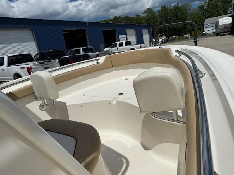 Slide: The Image of 2016 Pioneer 197 Islander boat interior with seating, parked near blue warehouse. - 2