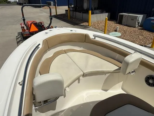 Slide: The Image of 2016 Pioneer 197 Islander boat interior with beige seating, parked near a tractor. - 6