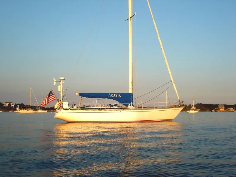 The Image of 1973 Nautor Swan 44 sailboat with blue cover, anchored in calm waters at sunset. - 0