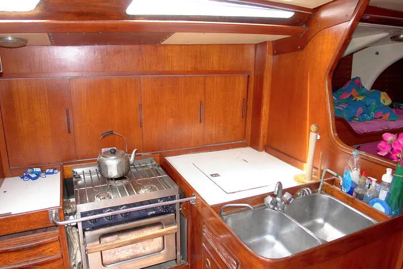Slide: The Image of 1973 Nautor Swan 44 yacht kitchen with wooden cabinetry, stove, and double sink. - 15