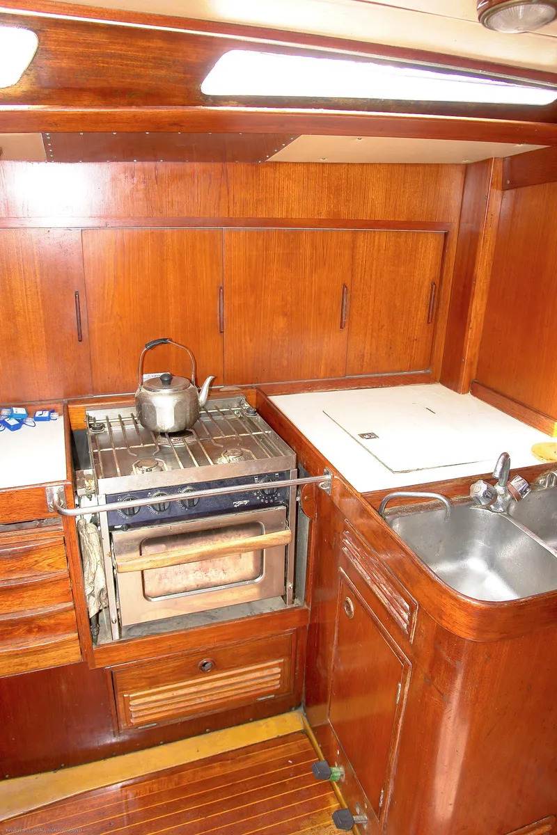 Slide: The Image of 1973 Nautor Swan 44 yacht kitchen with wooden cabinetry, stove, and sink. - 16