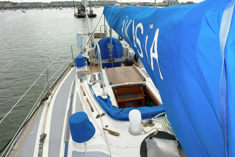Slide: The Image of 1973 Nautor Swan 44 sailboat with blue cover, docked in a calm harbor. - 24