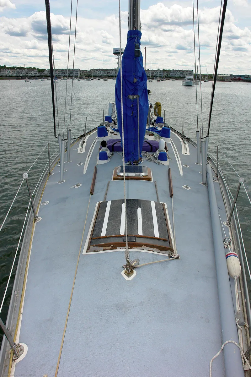 Slide: The Image of 1973 Nautor Swan 44 yacht deck with blue sail cover, docked on calm water. - 25