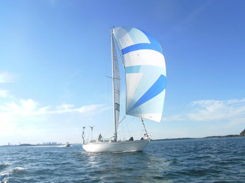 Slide: The Image of 1973 Nautor Swan 44 sailboat with blue and white spinnaker on open water. - 3