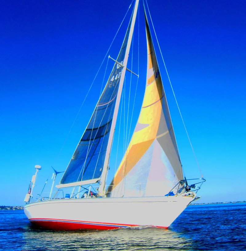 Slide: The Image of 1973 Nautor Swan 44 sailboat with colorful sails on open water under clear blue sky. - 33