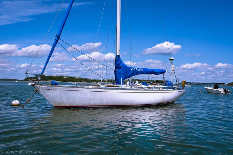 Slide: The Image of 1973 Nautor Swan 44 sailboat anchored on calm water under a clear blue sky. - 5