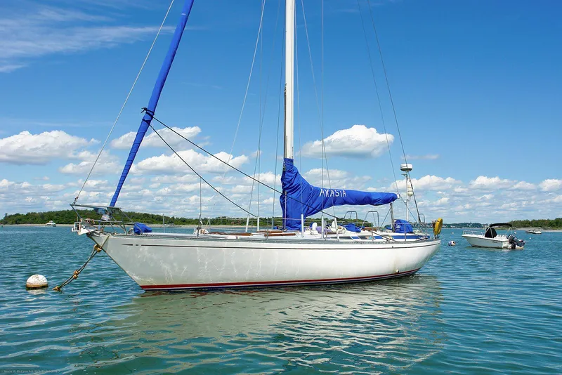 Slide: The Image of 1973 Nautor Swan 44 sailboat anchored on calm water under a clear blue sky. - 6
